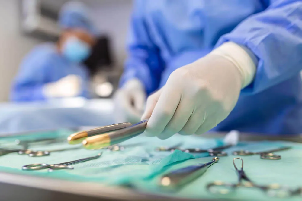 Nurse holding surgical instruments in an operating room, ready for surgery