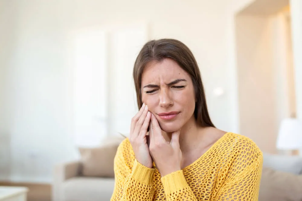 Young woman holding her cheek in pain from toothache
